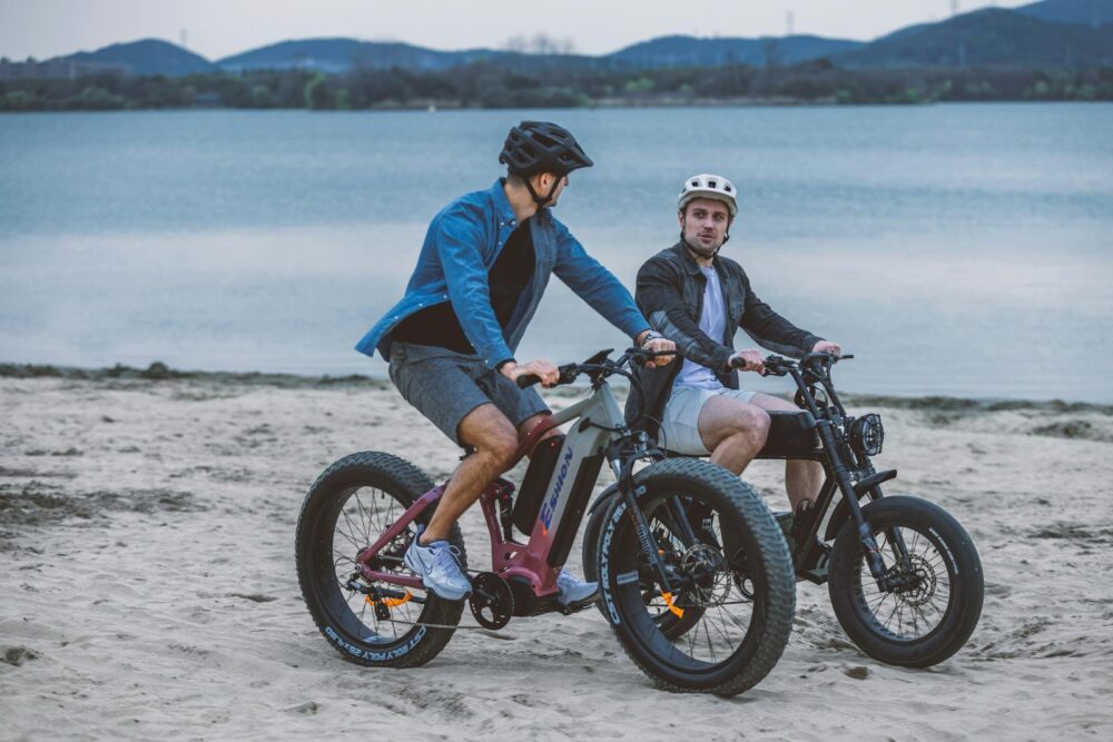 Two Young Men Riding Electric Bikes along a Sandy Coastline