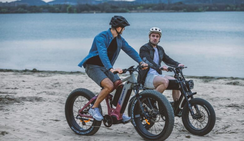 Two Young Men Riding Electric Bikes along a Sandy Coastline